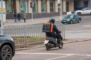 Dnepropetrovsk, Ukraine - 02.10.2022 A delivery service courier with a thermal bag on a bicycle rides around the city. Home food delivery. photo