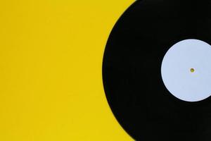 Close up of black old vinyl record play disc vintage on a yellow background with copy space for text. Retro LP history, nostalgia concept. Sound technology for DJ to mix music. Flat lay, top view photo