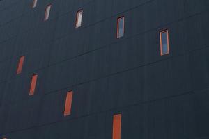 Architecture fragment of geometry with windows in orange frame on deep grey background. Pattern texture of facade in modern building. photo