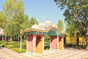 Square with trees and colorful Indian style arch in city park. Pedestrian zone for walking. Urban planning, public space concept. Town recreation area. Architecture design comfortable garden. Footpath photo