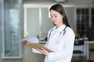 Asian woman doctor look at the opened document in clipboard