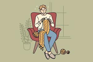 Home hobbies and knitting concept. Young smiling man cartoon character sitting at home in armchair knitting scarf vector illustration