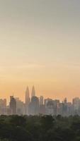 vertikale zeitraffer landschaftsansicht von kuala lumpur stadtzentrum innenstadtbezirk mit vielen wolkenkratzergebäuden hochhäuser im modernen stil türme mit wunderschönem vanillesonnenuntergang sonnenaufgang dämmerungshimmel video