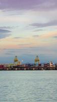 verticaal timelapse van diep zee haven met vrachtschip bezig met laden en lossen met veel lading containers,import en exporteren vracht vervoer door houder schip video