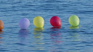 drôles de ballons colorés nageant sur l'eau de mer video