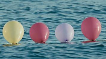 lustige bunte luftballons, die auf dem meerwasser schwimmen video