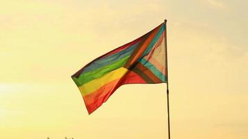 la bandera lgbt del arco iris ondea sobre el poste en el fondo del cielo del atardecer. concepto de libertad y diversidad de género video