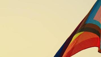 Rainbow LGBT flag flutters atop the pole in the background of the sunset sky. concept of freedom and gender diversity video