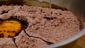 el huevo de gallina cae en cámara lenta en el primer plano de la harina de cacao. receta paso a paso para hacer galletas de chocolate caseras o bizcocho de brownies. video