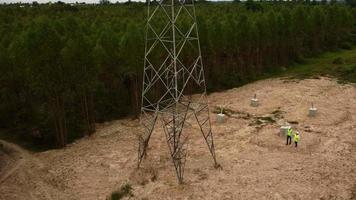 des ingénieurs environnementaux masculins et féminins inspectent la forêt pour le développement du site de construction de la fondation du poteau haute tension. video