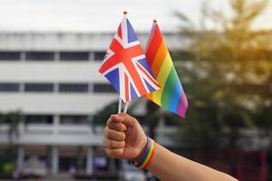 Rainbow flag and the national flag of United Kingdom Hold it in the hands of LGBT people wearing rainbow wristbands. soft and selective focus. photo