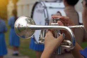 rlose-up de la mano del estudiante presionando el botón de una trompeta para perseguir una nota musical, tocando una canción mientras practica para un desfile escolar. enfoque suave y selectivo. foto