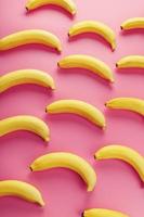 Yellow bananas scattered on pink background with texture pattern