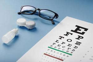 Glasses with Contact Lenses, drops and an Optometrist's Eye Test Chart On a Blue Background. photo