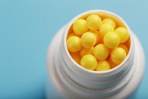 Vitamins are yellow in a white jar on a blue-blue background. photo