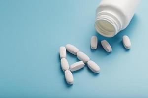 The letter of vitamin A in capsules pour out from the jar on a blue background. photo