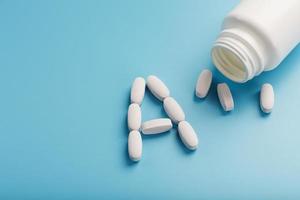 Vitamin A pills fell out of a white jar on a blue background. photo