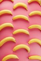 Geometric pattern of bananas on a pink background. The view from the top.
