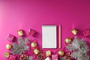 Notepad in holiday toys and decorations on pink christmas background. photo