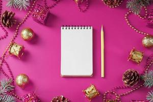 Notepad in holiday toys and decorations on pink christmas background. photo