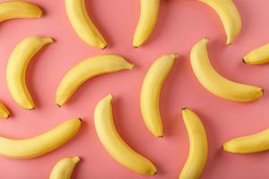 Bright pattern of yellow bananas on a pink background. photo