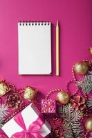 Notepad in holiday toys and decorations on pink christmas background. photo