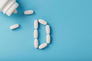 The letter of vitamin D in capsules pour out from a jar on a blue background. photo