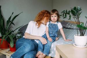 Young mother and child have fun and fool around at home on the bed photo