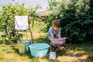 Little preschool girl helps with laundry. Child washes clothes in garden photo