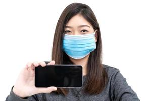 Woman wearing protective mask holding and showing mobile phone photo