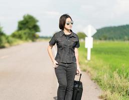 Woman with luggage hitchhiking along a road photo