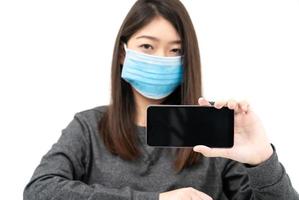 Woman wearing protective mask holding and showing mobile phone photo