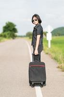 Woman with luggage hitchhiking along a road photo