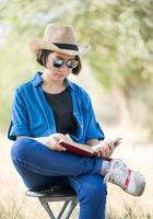 mujer usa sombrero y lee el libro en la silla foto