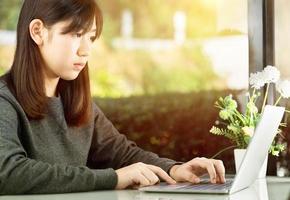 Teenage student using laptop doing homework at home photo