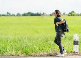 Woman with backpack hitchhiking along a road photo