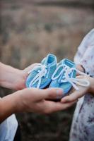 father and mother hold newborn's shoes close-up photo