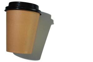 Cardboard coffee cup with plastic lid with hard shadow on white background. isolated object. Template with copy space. The concept of ecology, recycling, environmental protection. photo