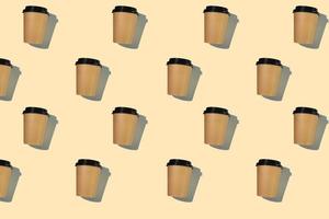 Pattern of cardboard coffee cups with a plastic lid with a hard shadow on a beige background. The concept of ecology, recycling, environmental protection. photo