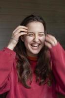 young beautiful girl with long hair in a red pullover laughs, the concept of love, joy, mental health photo