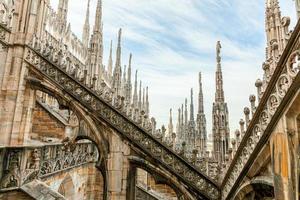 Roof of Milan Cathedral Duomo di Milano with Gothic spires and white marble statues. Top tourist attraction on piazza in Milan, Lombardia, Italy. Wide angle view of old Gothic architecture and art. photo