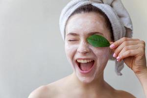 Woman face with green leaf and cream or nourishing mask photo