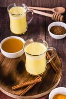 Turmeric honey golden milk in glasses on the table. Home treatment, improve immunity. Vertical view photo