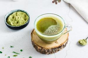 Organic green matcha tea in a cup on a tree trunk on the table. Close-up