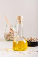 Organic sunflower oil in a bottle and seeds in a bowl on the table. Vegetarian food. Vertical view photo