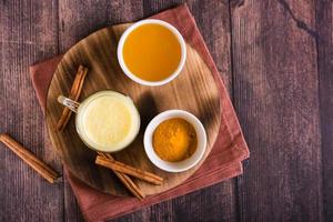 Healthy golden milk with turmeric and honey in glasses on the table. Home treatment. Top view photo