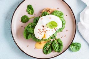 Appetizing sandwich with poached egg and spinach on a plate. Flexetarian Diet. Top view. Close-up photo
