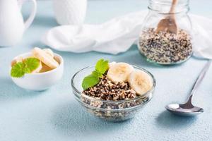 Boiled quinoa mix with banana and mint in a bowl on the table. Homemade healthy breakfast. photo