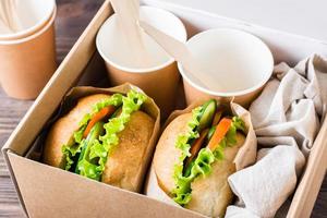 hamburguesas vegetarianas con verduras frescas y lechuga en un bollo en una caja. entrega de comida rápida. foto