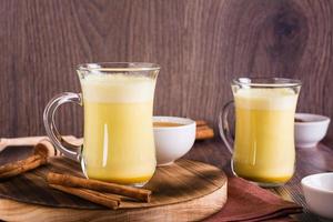 Healthy golden milk with turmeric and honey in glasses on the table. Home treatment. photo
